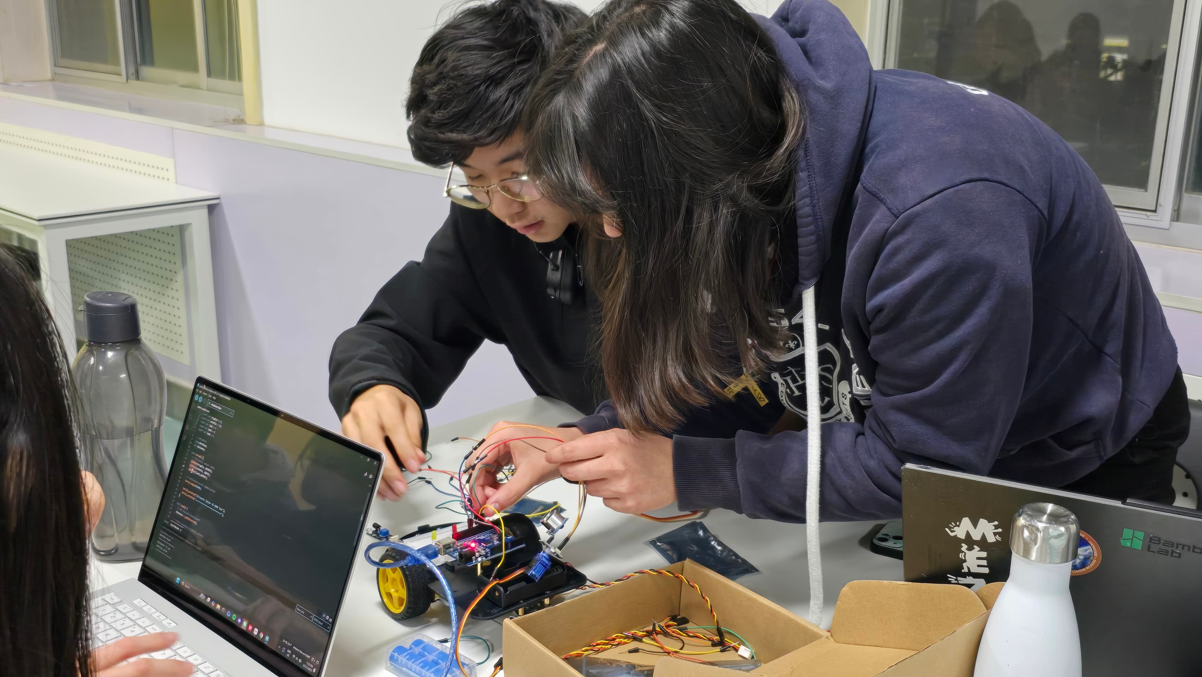 Robotic-arm prototype presented beside a mechanism reference during the new-member program